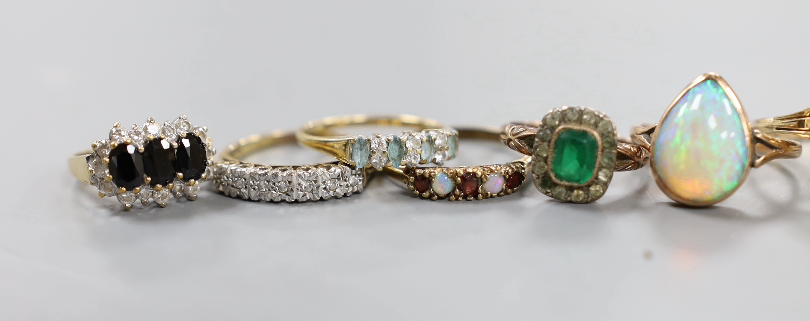A modern 9ct white gold, blue topaz and diamond set pendant, ten assorted modern 9ct and gem set rings, a yellow metal and opal ring and a quartz set pendant.